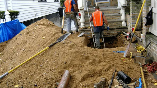 Contractors performing foundation protection and exterior drainage excavation near residential home steps in Tampa, FL