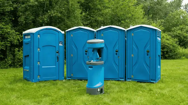 Four blue portable toilets and a matching hand washing station on grass near trees, a common sight at local outdoor events in Tampa, FL