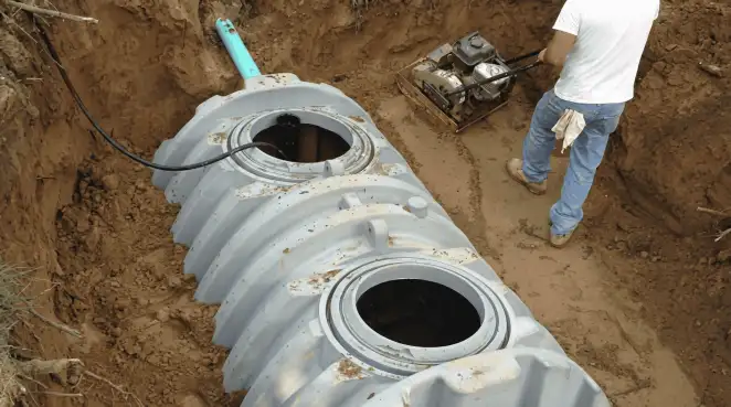 Septic tank installation showing a technician compacting soil around a new poly septic tank in an excavation pit in Tampa, FL